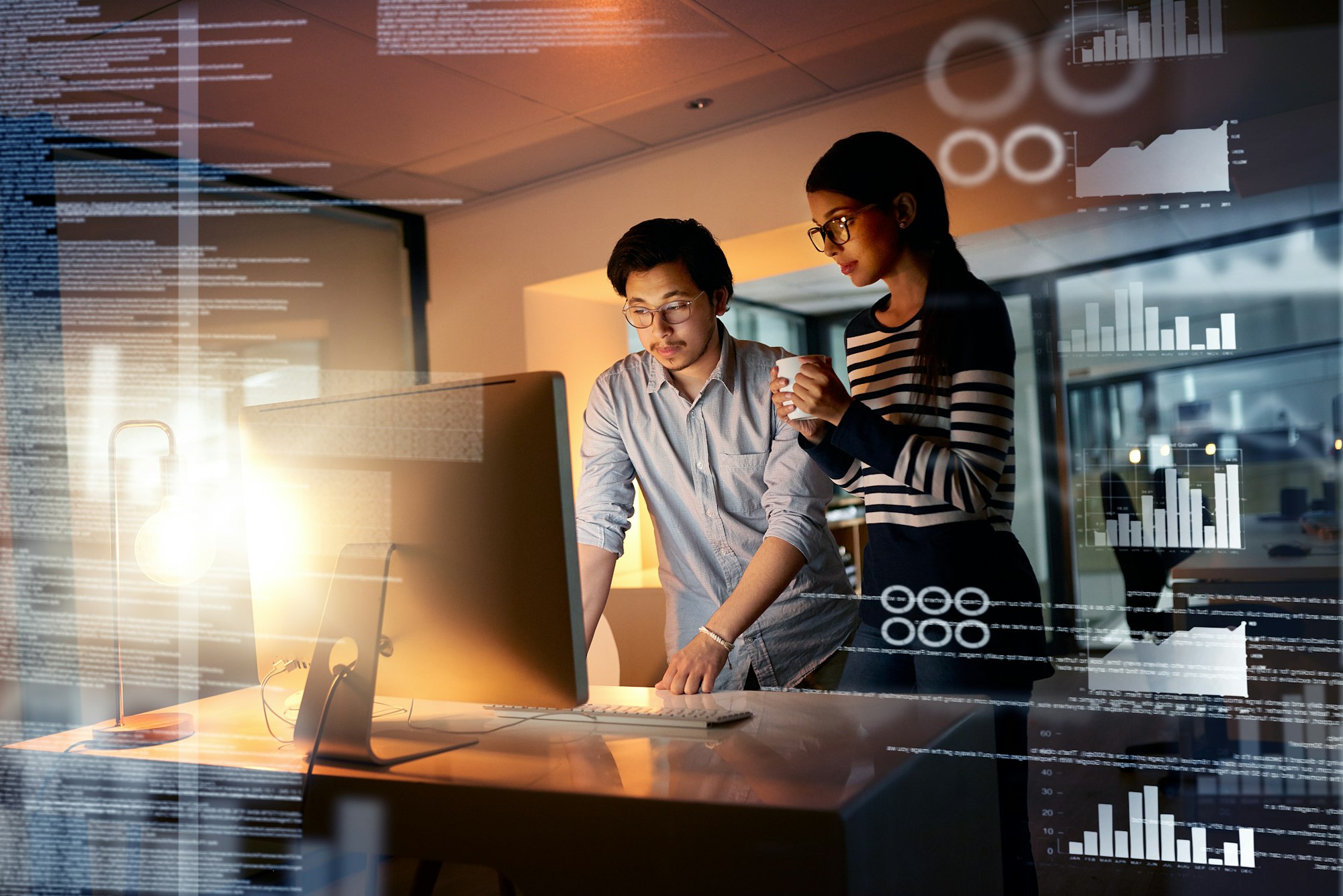 Shot of colleagues connecting to a user interface while working in an office at night